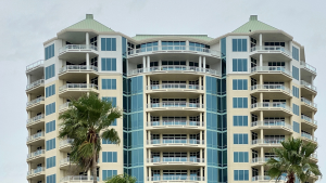 Ein Mehrfamilienhaus bei dem einzelne Immobilien als Kapitalanlage genutzt werden, man sieht außerdem Palmen und viele Balkone