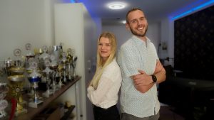 Eine Frau und ein Mann lächeln mit verschränkten Armen in die Kamera.