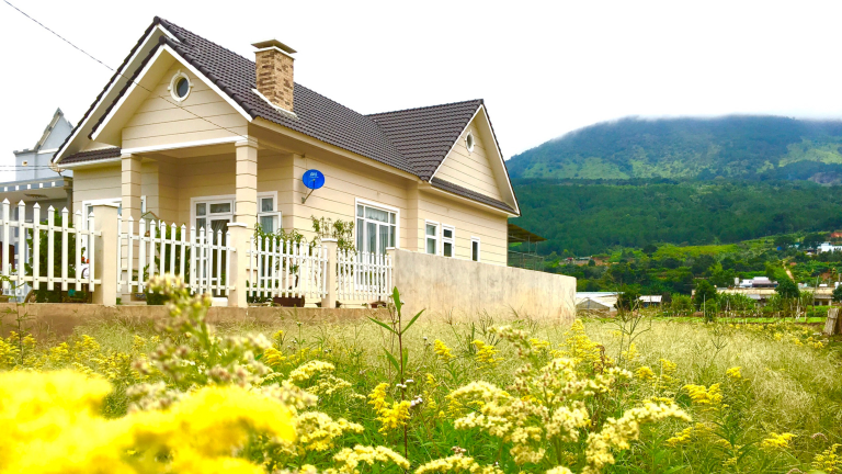 Ein Haus, welches auf dem Land, auf den Bergen steht. Viele Blumen die das Haus umrunden.