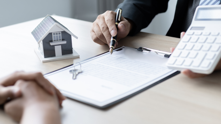 Eine Person, die einer anderen Person ein Haus verkauft, dabei nennt er 8 Fehler beim Immobilienkauf.